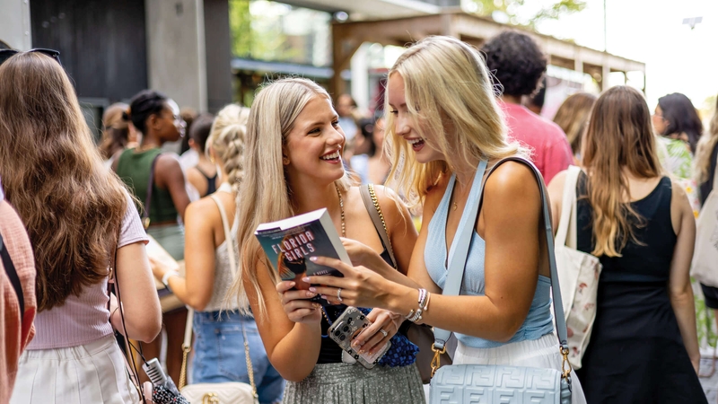 two women looking at a book amongst a group