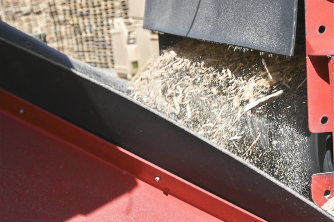 Recycled pallet wood being fed into J.C. Pallet's industrial wood chipper during the mulch processing run