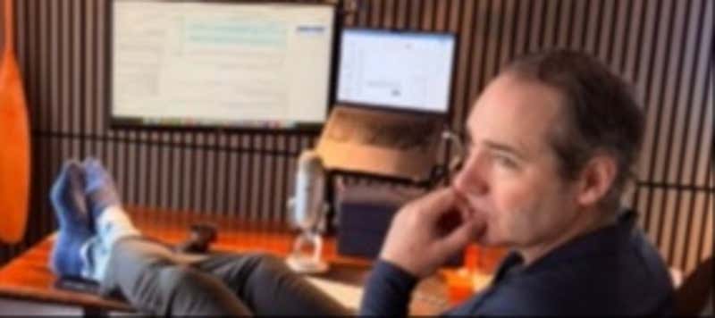 A sales leader with their feet up on the desk while a screen displays text, illustrating the fantasy of AI doing the work