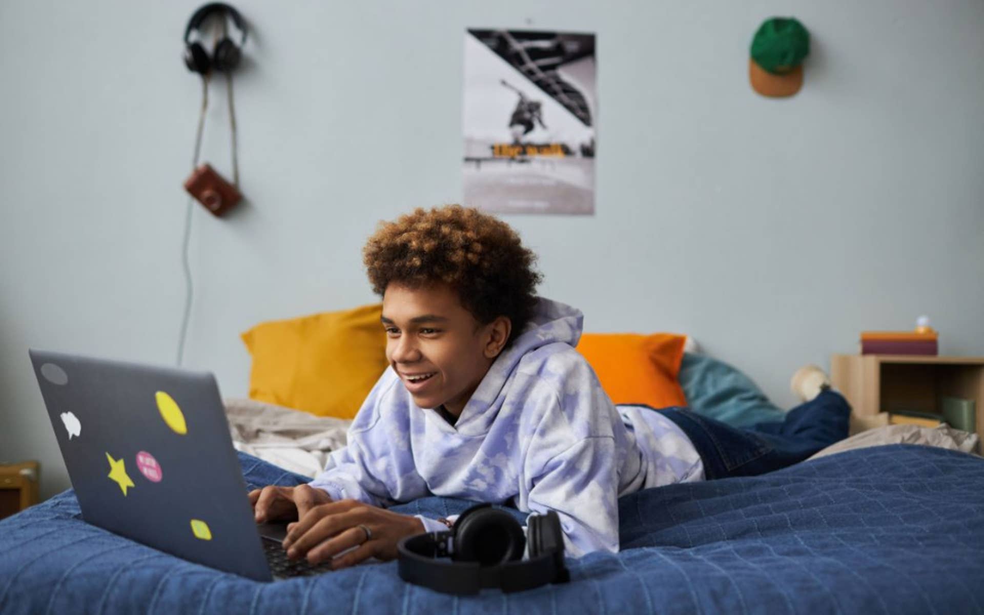 teen boy on laying on bed with laptop