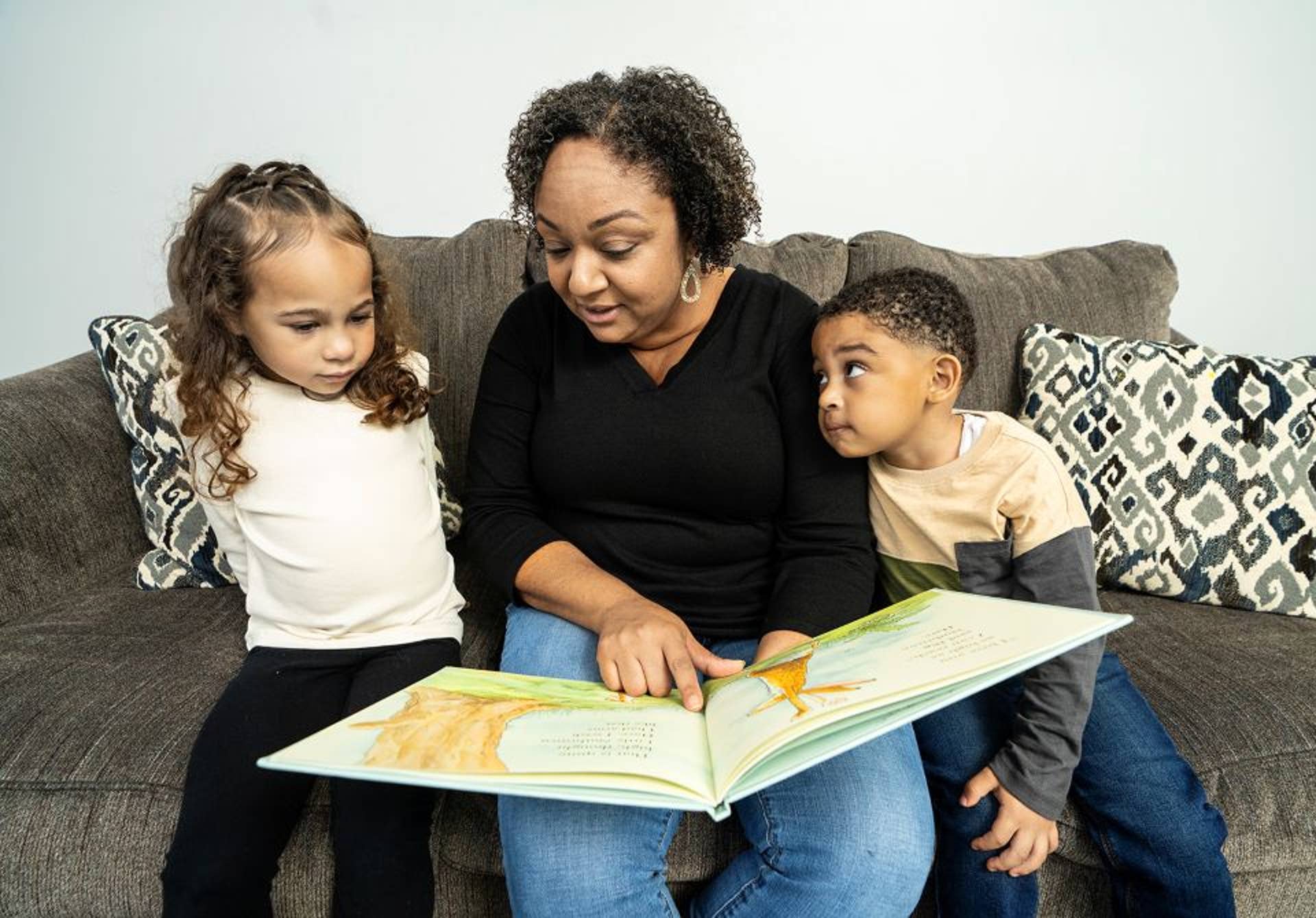 Woman reading to young boy and girl