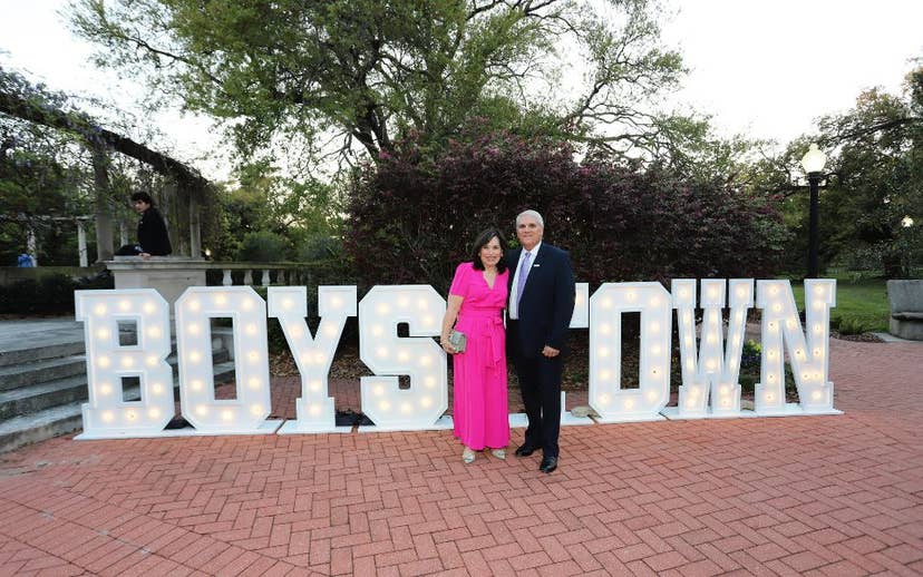 couple standing in from of Boys Town Light Sign
