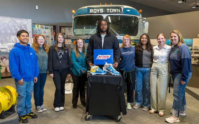 Adult male standing next to a bunch of students accepting a project they created