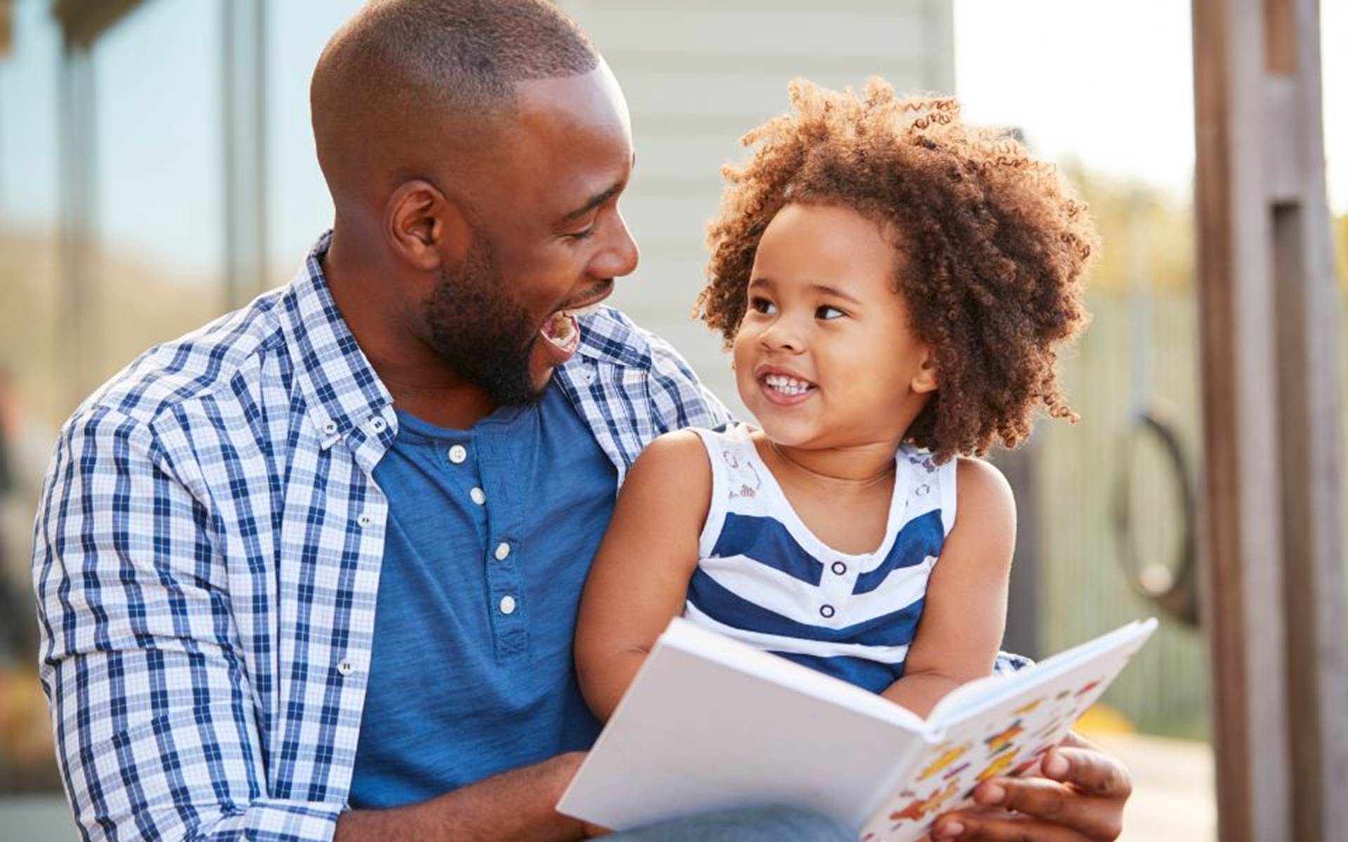 Father and younger daughter reading a book together