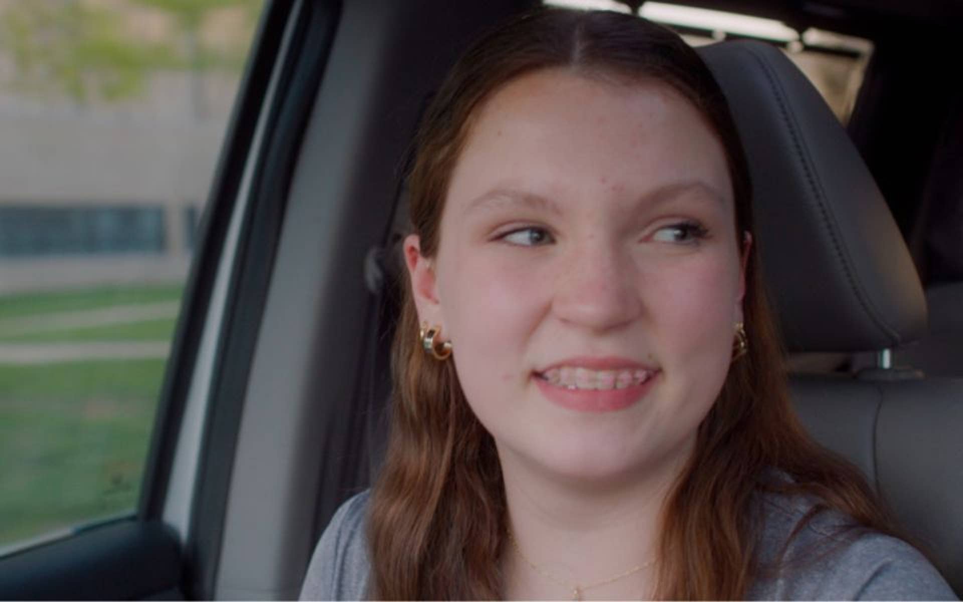 Girl smiling over at her mom sitting in the car