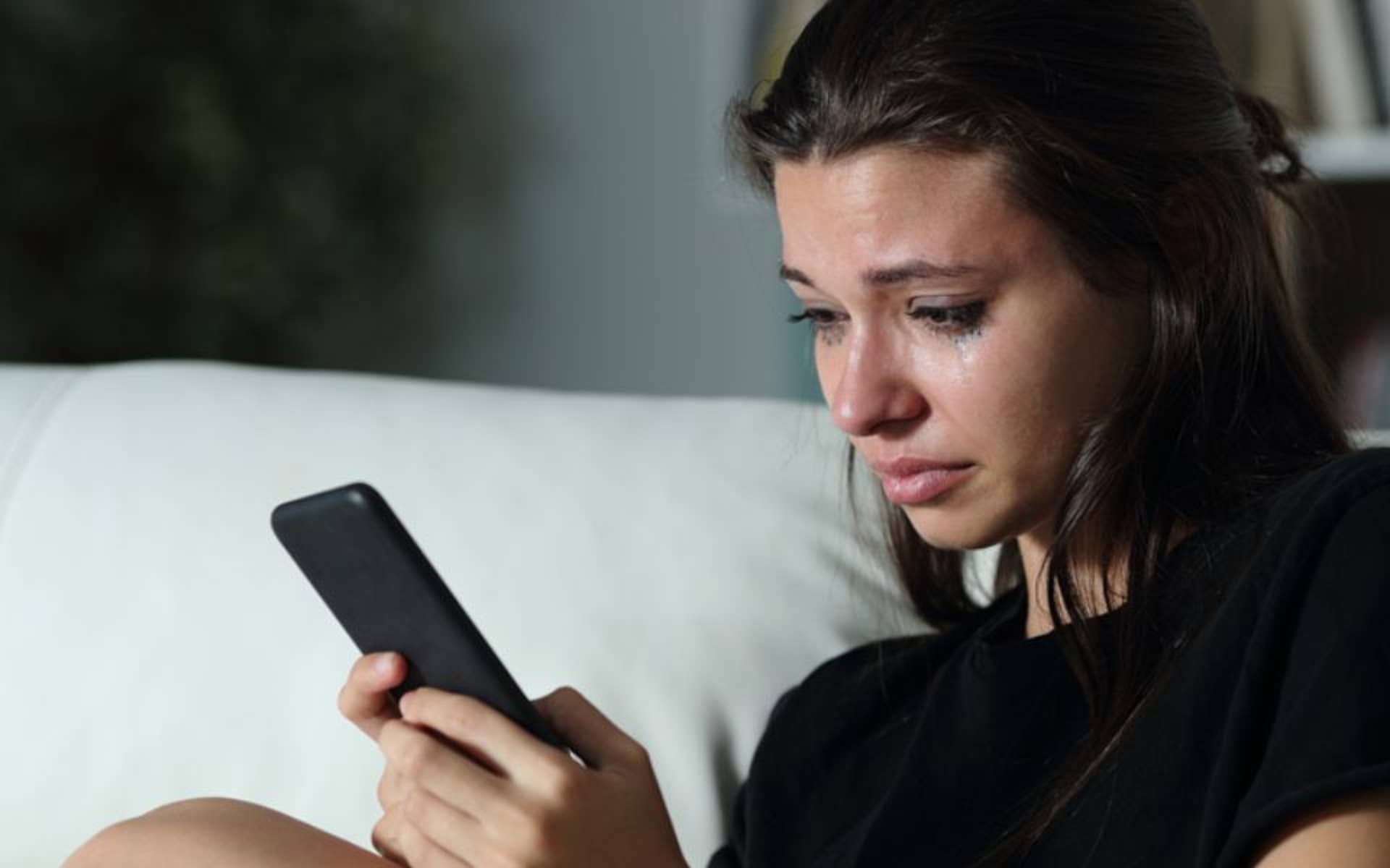 Young girl looking at her phone and is crying