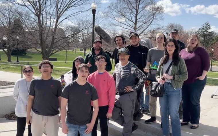 A group of students and adults holding film equipment outside