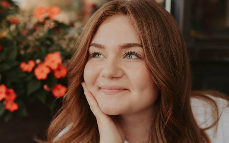 Redhead girl smiling with red flowers in the background