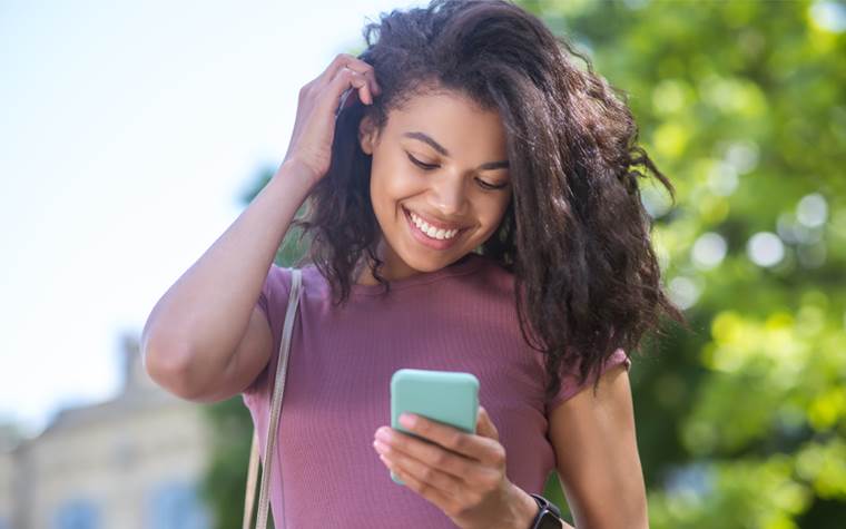 African American Teen Girl Smiling Looking at Her Phone