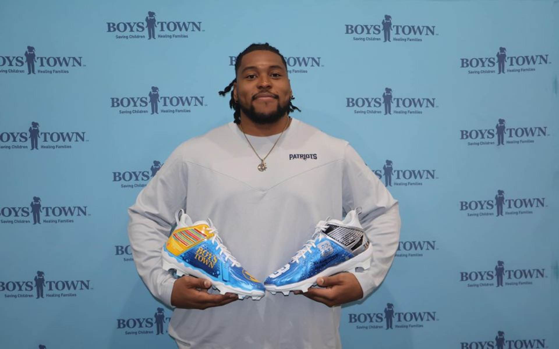 Football player holding sports cleats with Boys Town colors