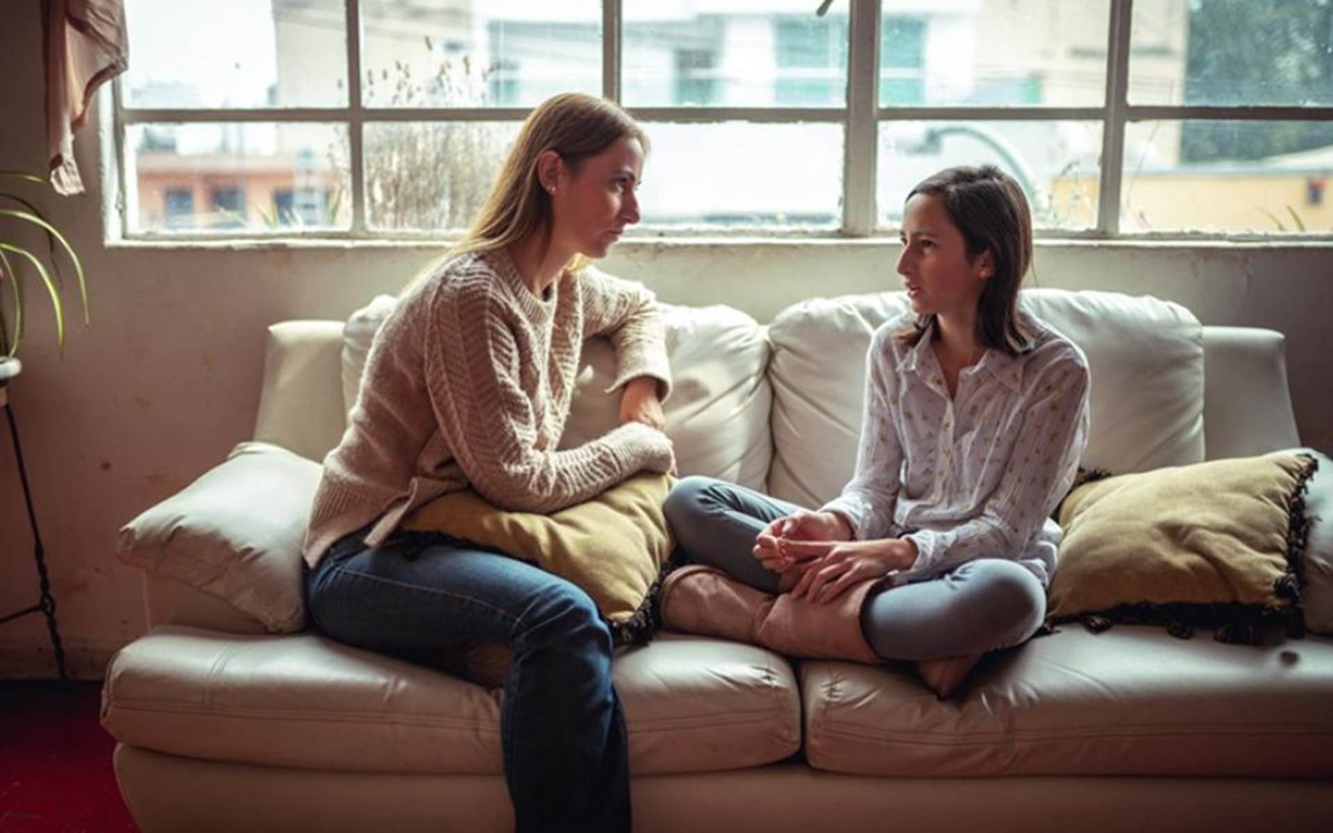 Mom and daughter talking to each other on a couch 