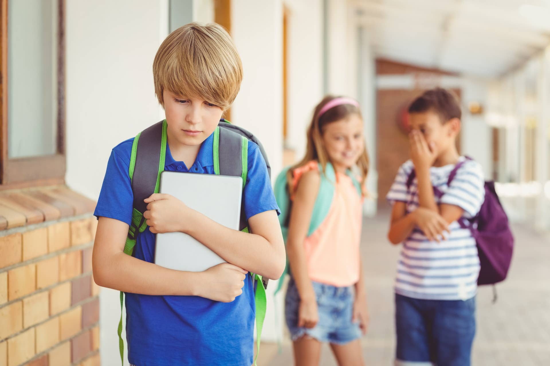 child holding notebook looking sad at school