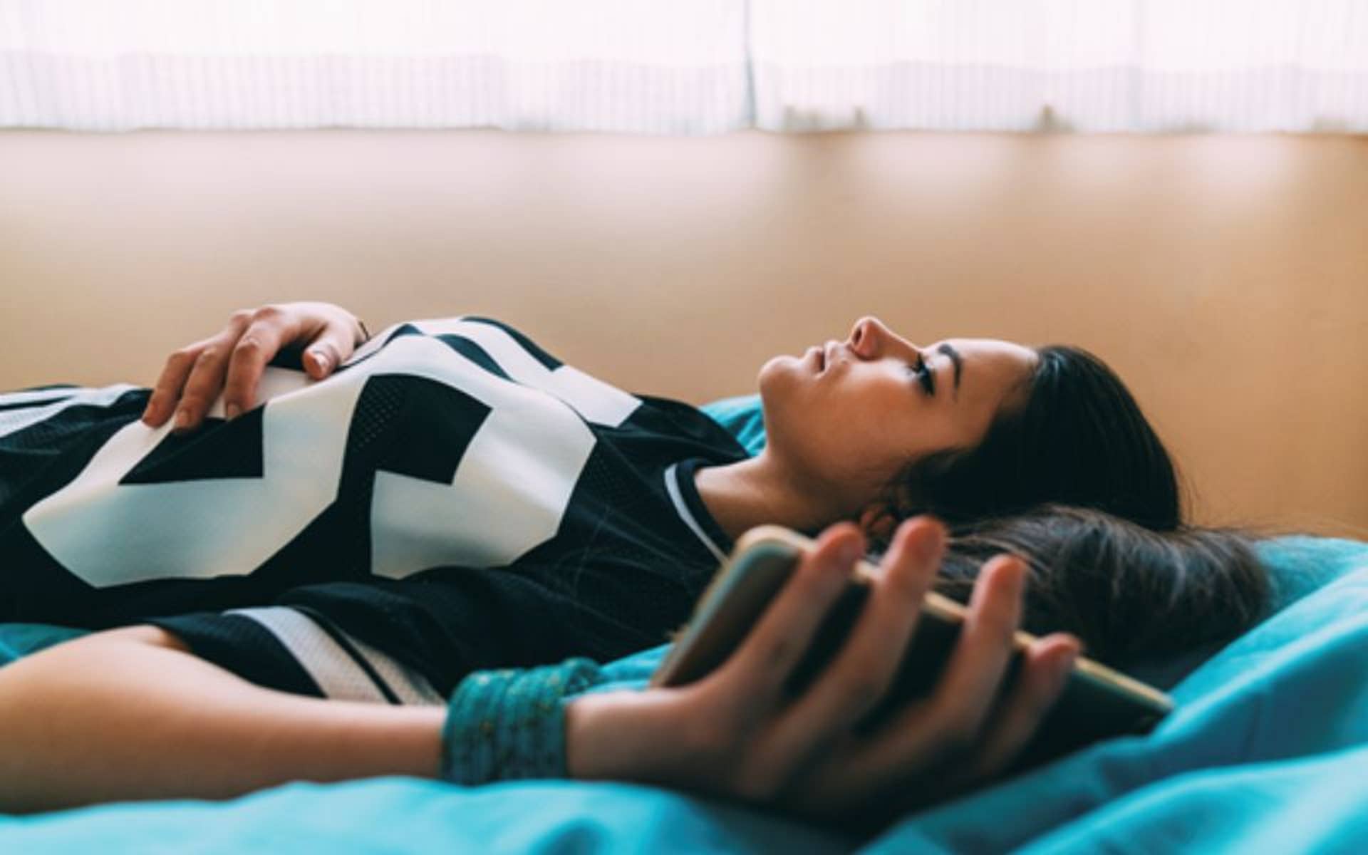 young teenager laying on bed with smart phone