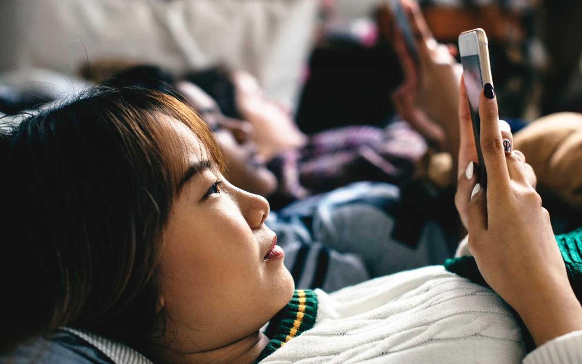young teenage girl with dark hair scrolling on phone