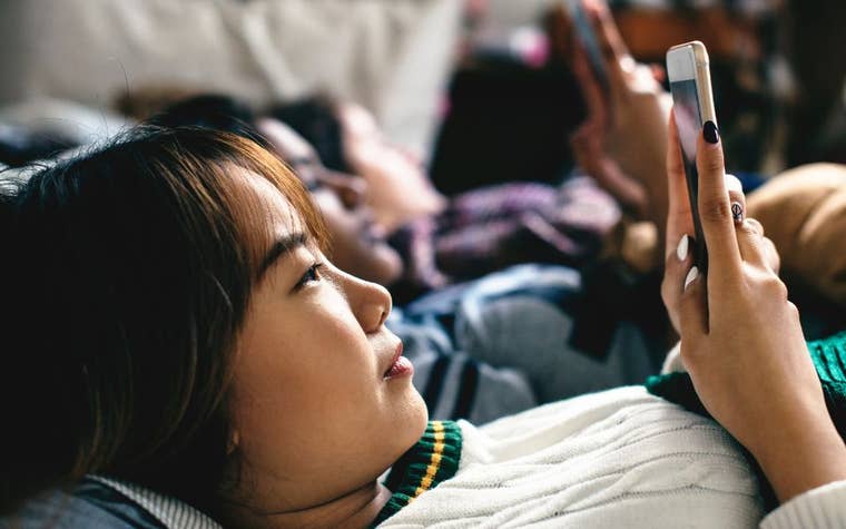 young teenage girl with dark hair scrolling on phone