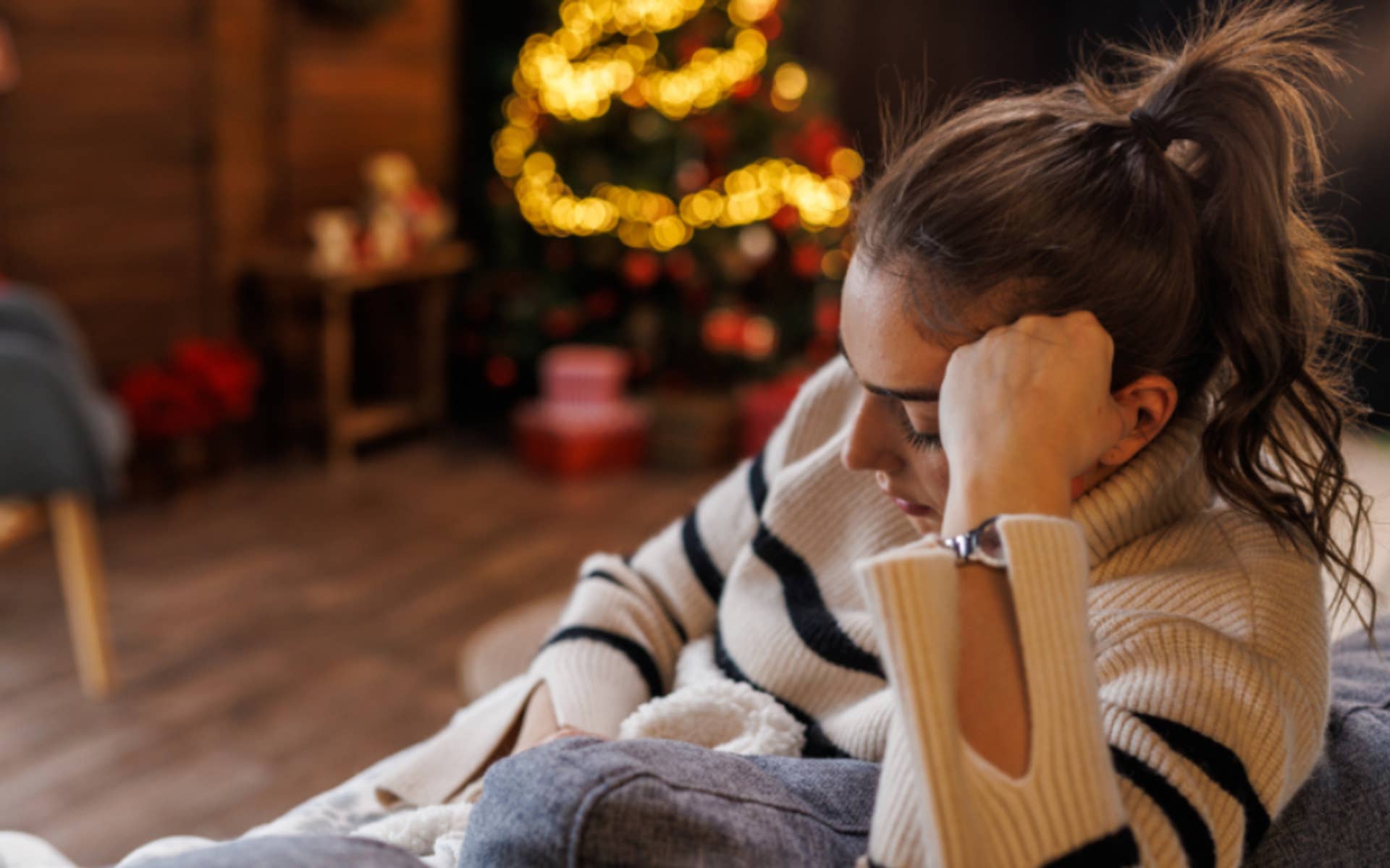 young woman sitting on couch looking sad and frustrated 