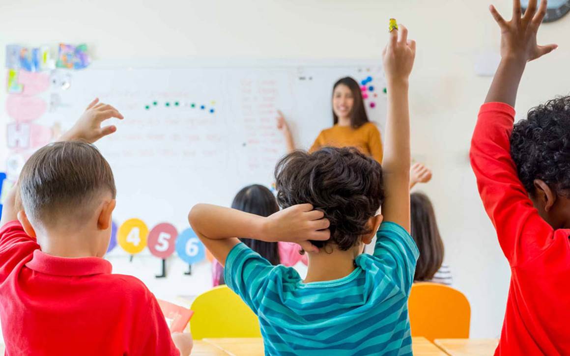 Kids raising their hands in the classroom