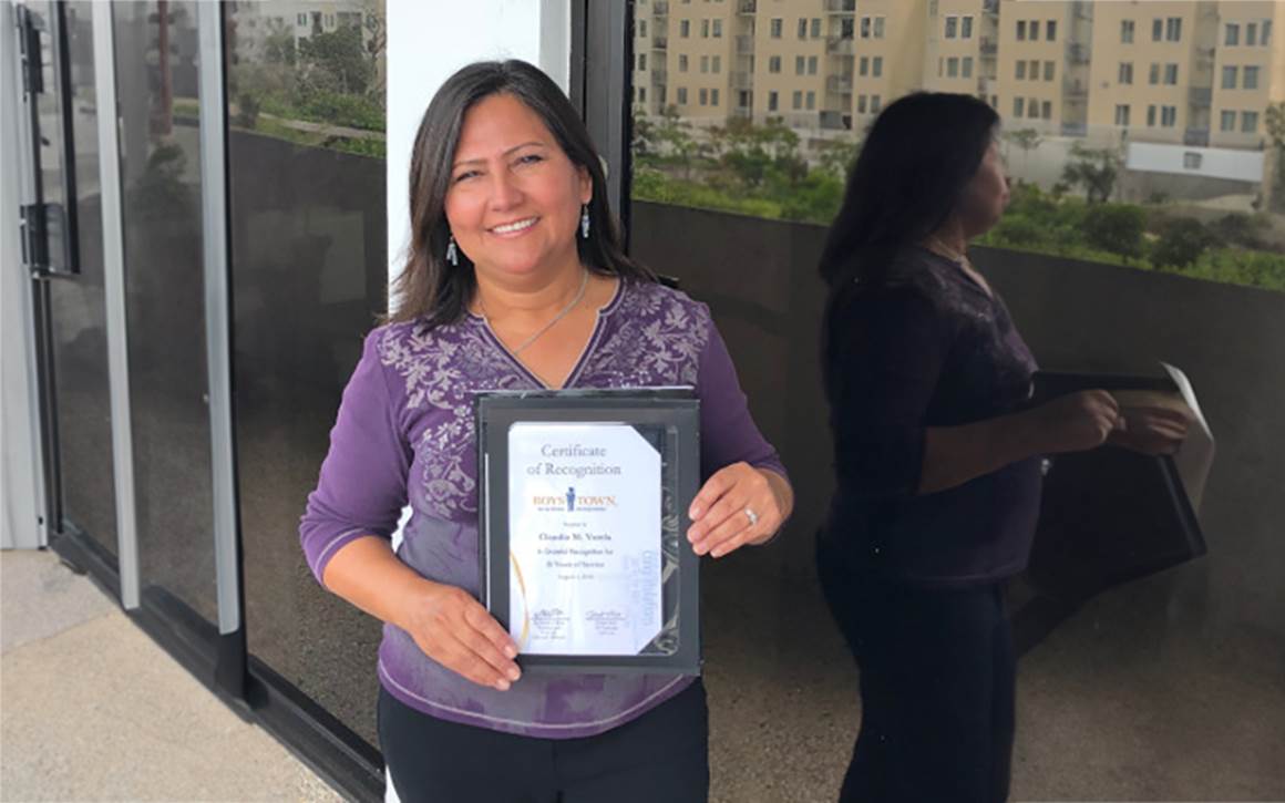 Claudia holding up her recognition plaque