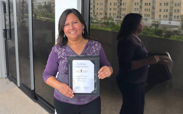 Claudia holding up her recognition plaque