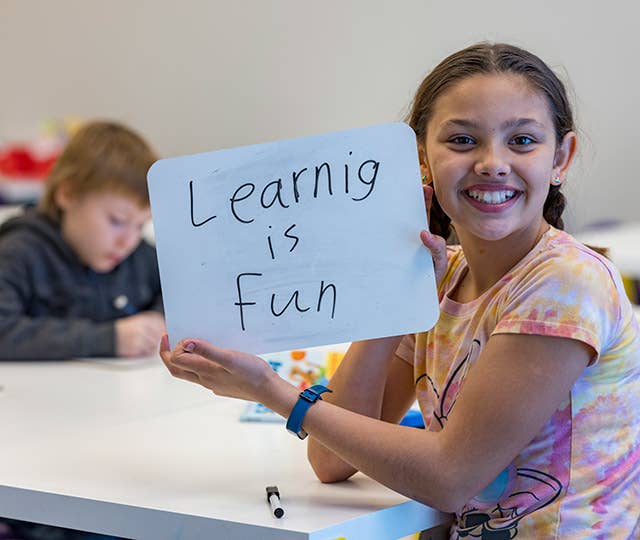 Girl holding up "Learning is fun" sign