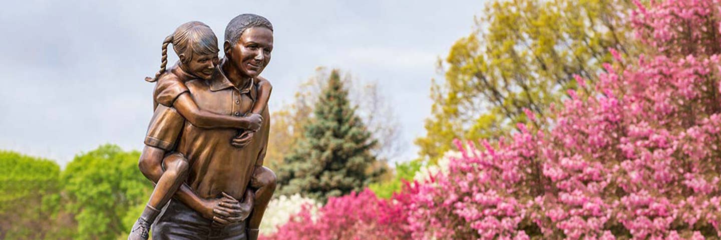 He aint heavy statue in front of spring bloom