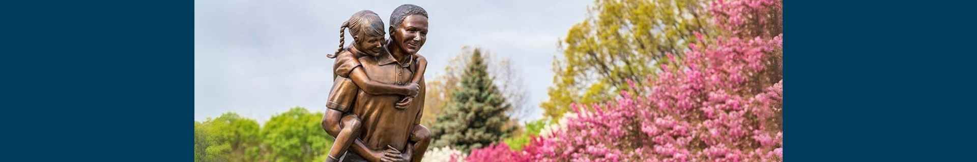 He aint heavy statue in front of spring bloom