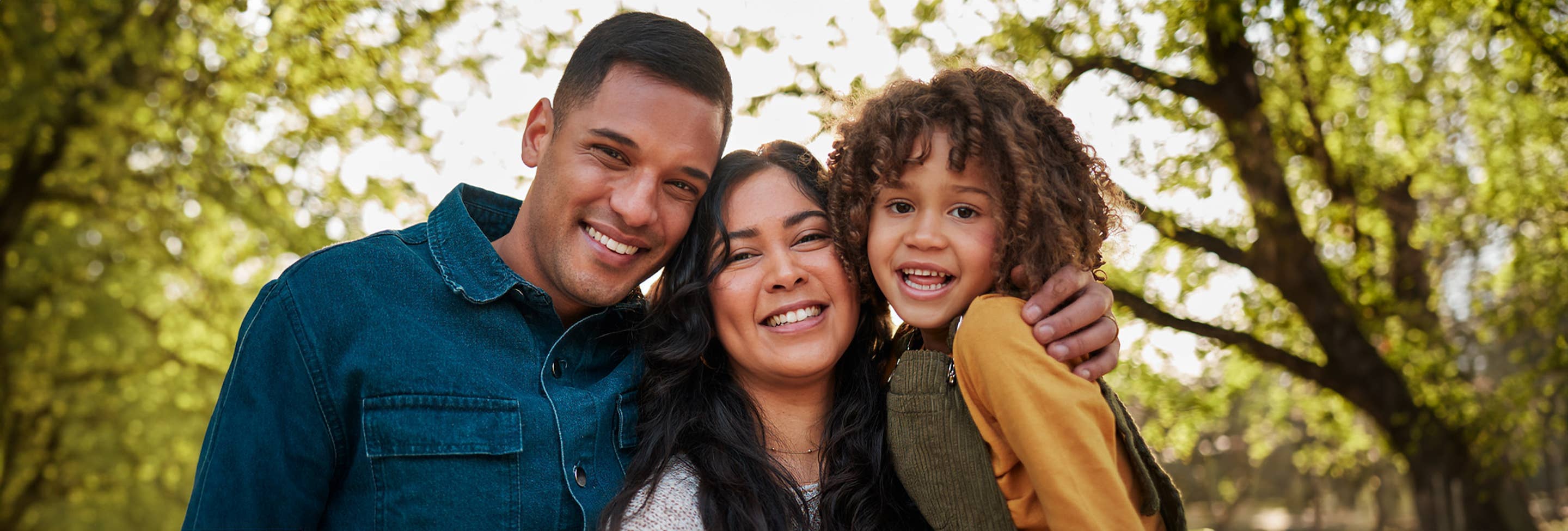 Family of three outside smiling