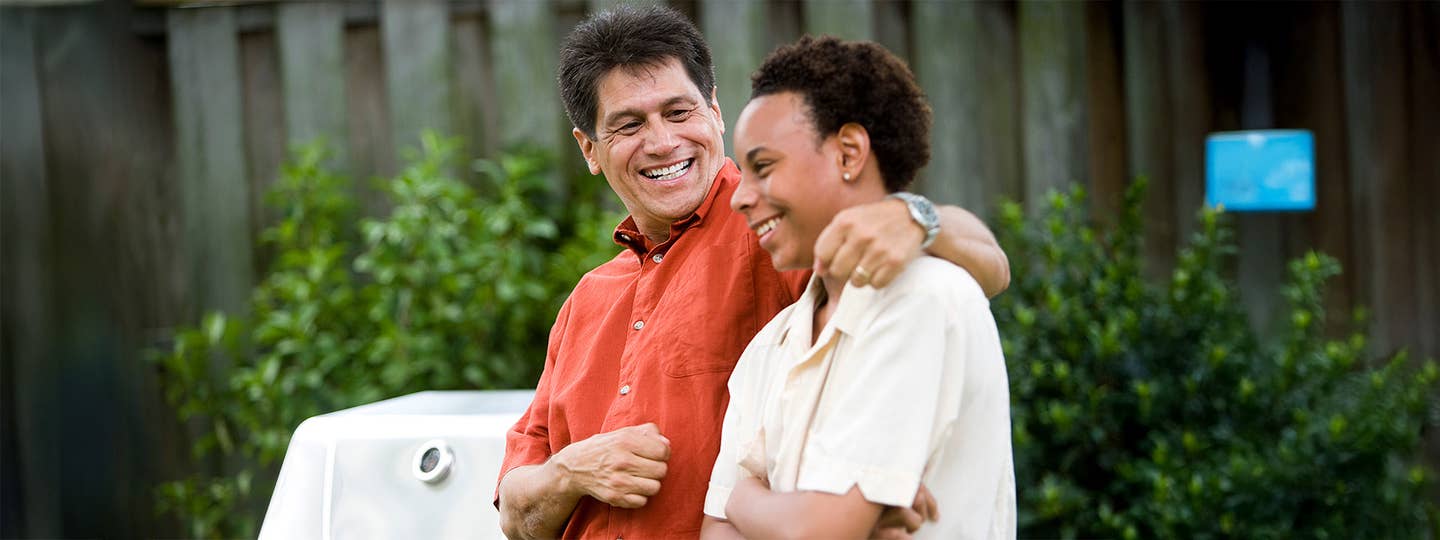 Man and young man hanging out, smiling on a bench