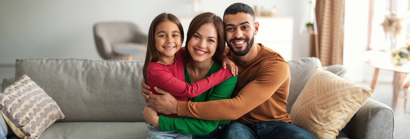 Family of three sitting on a couch. 