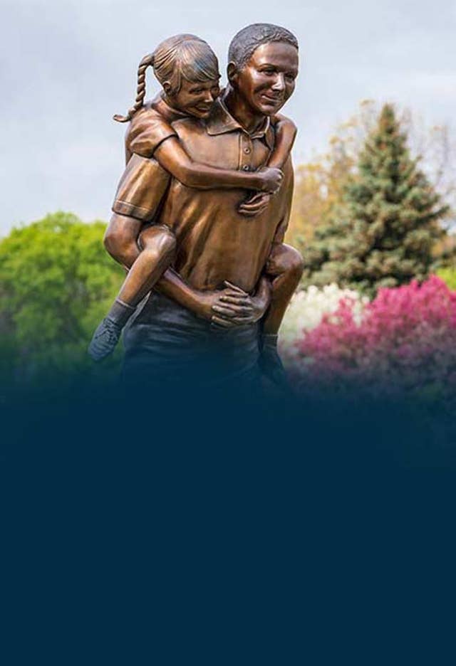 He aint heavy statue in front of spring bloom