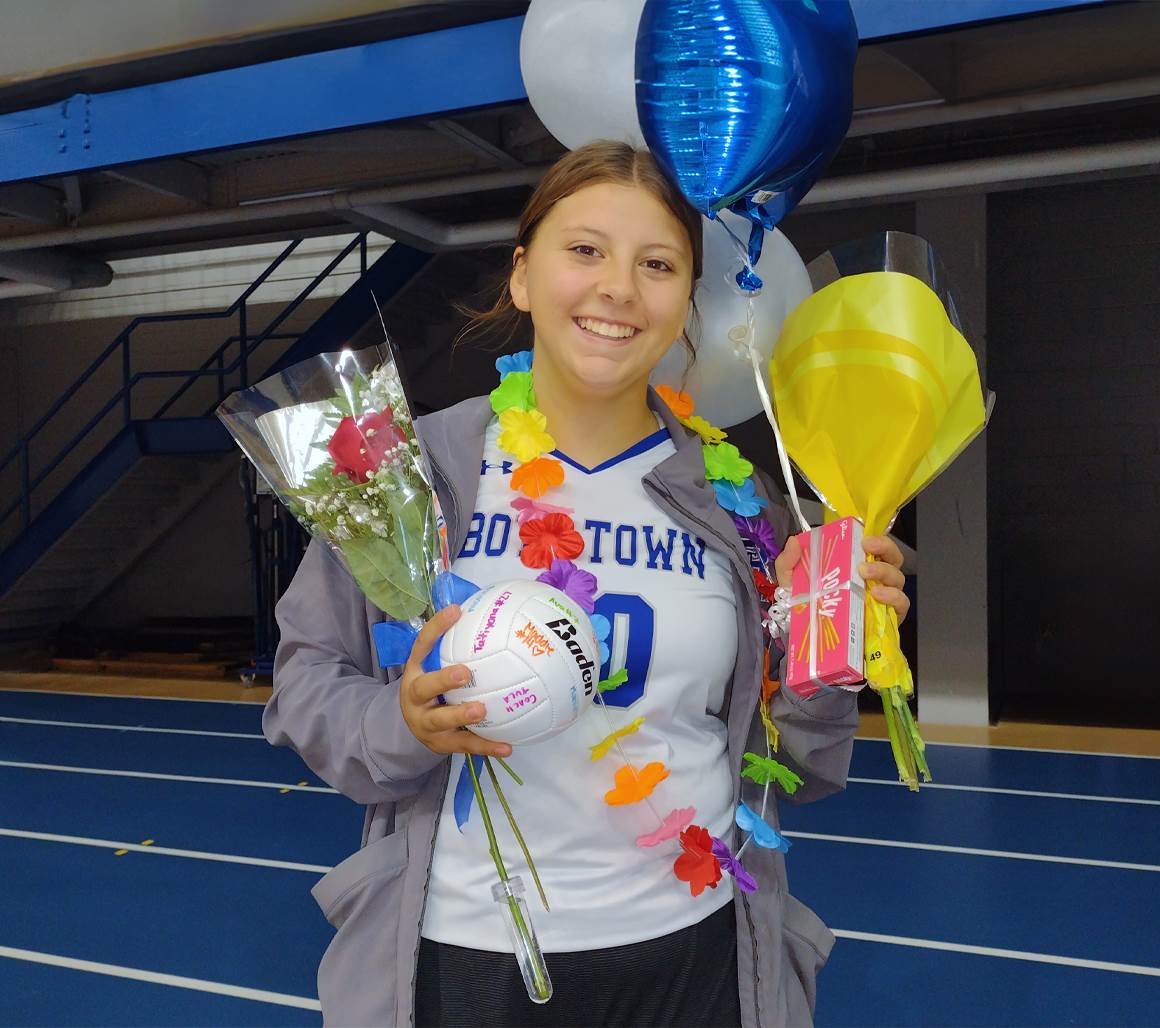 Photo of Lexi holding flowers, balloons, and awards