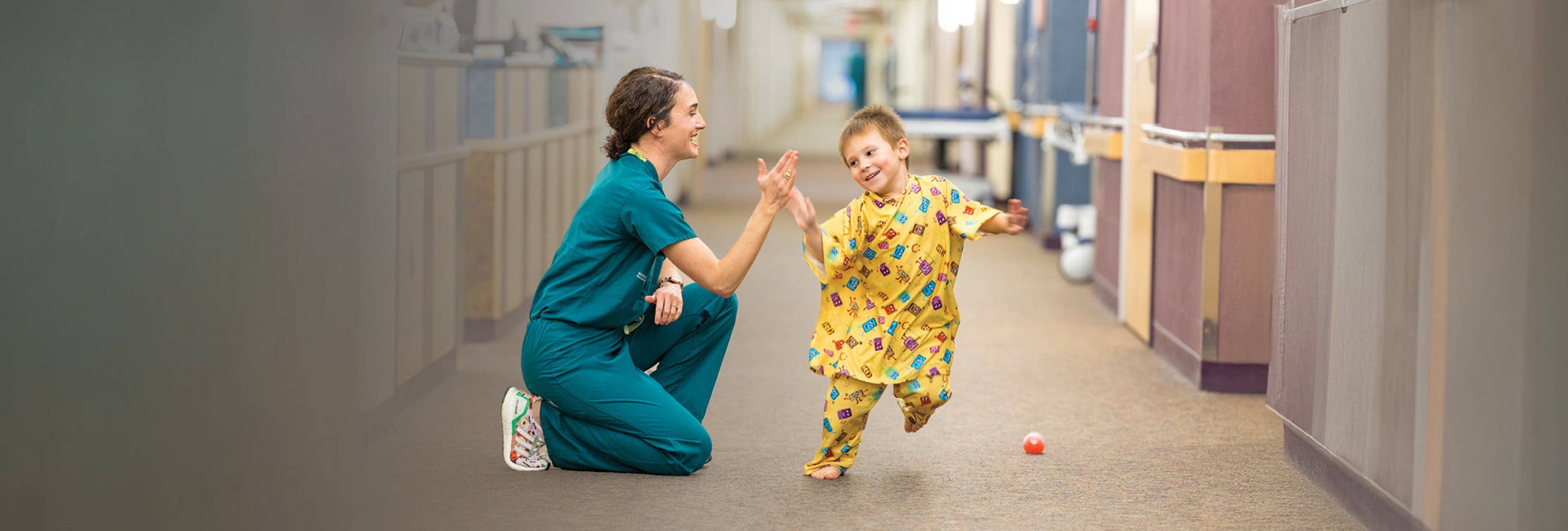 Physician and child high fiving in hallway