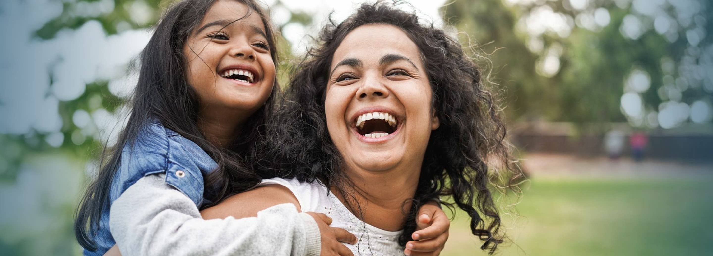 Mother giving daughter piggy back ride. laughing and smiling