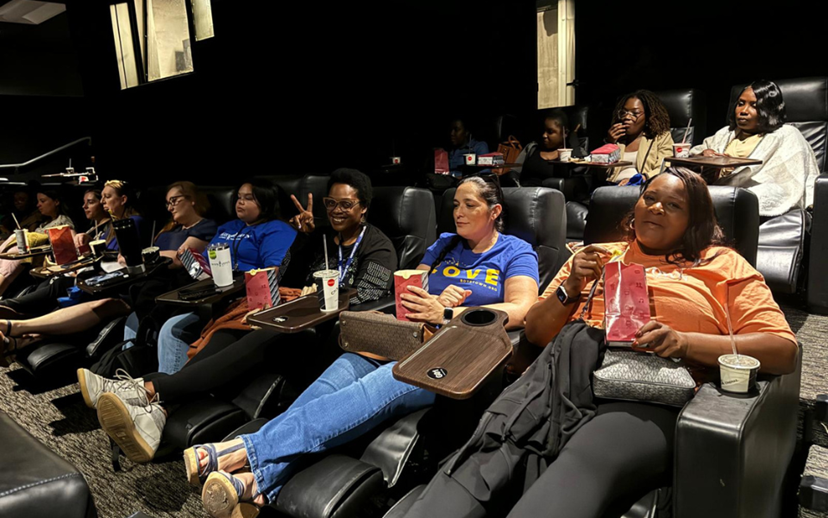 South Florida staff are seated in a movie theater, awaiting the start of the film.