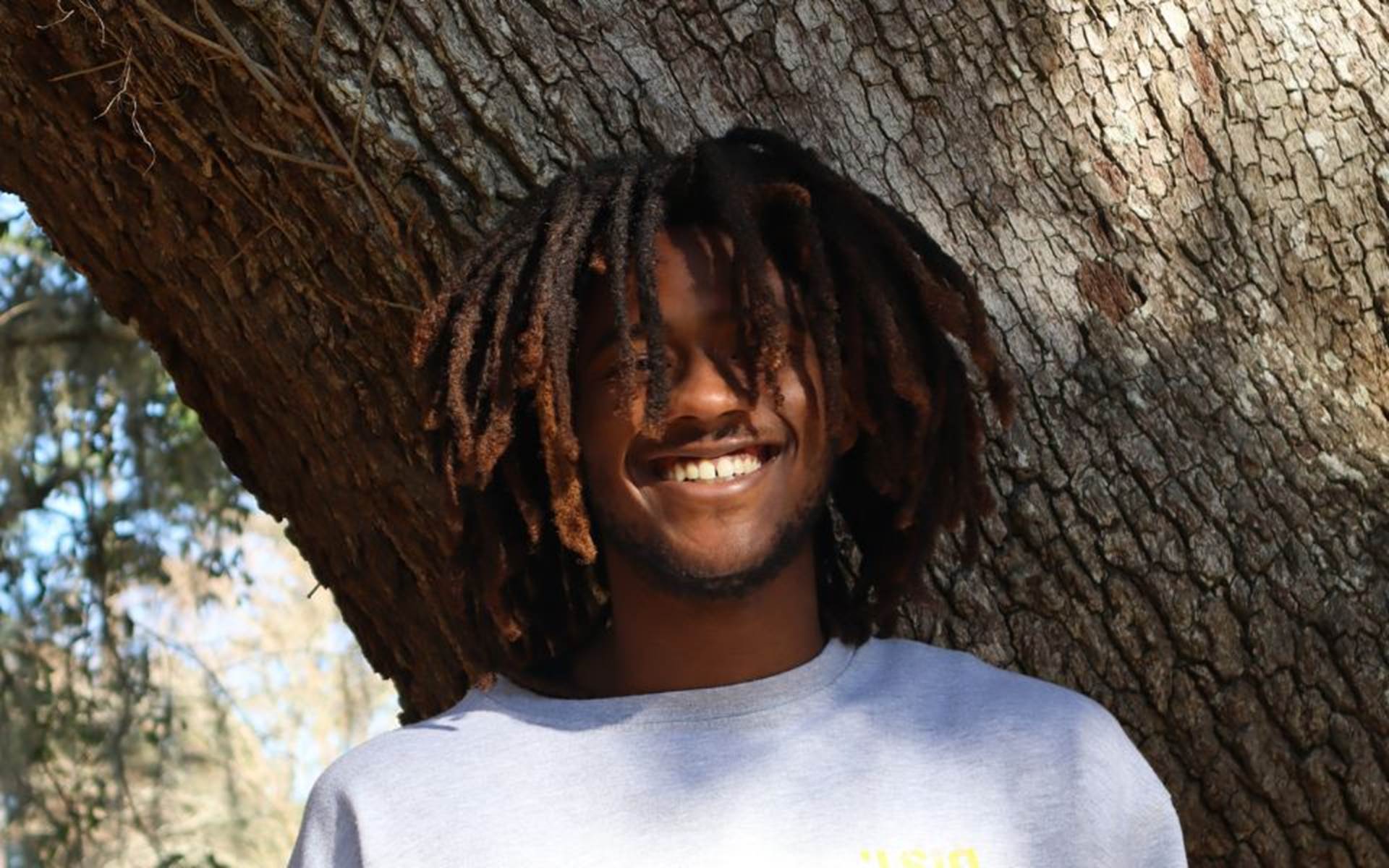 Terrance smiling in front of a tree