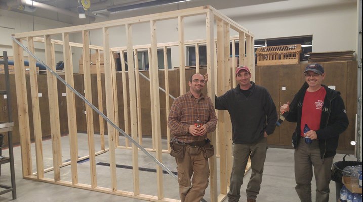 Men standing with a wooden structure