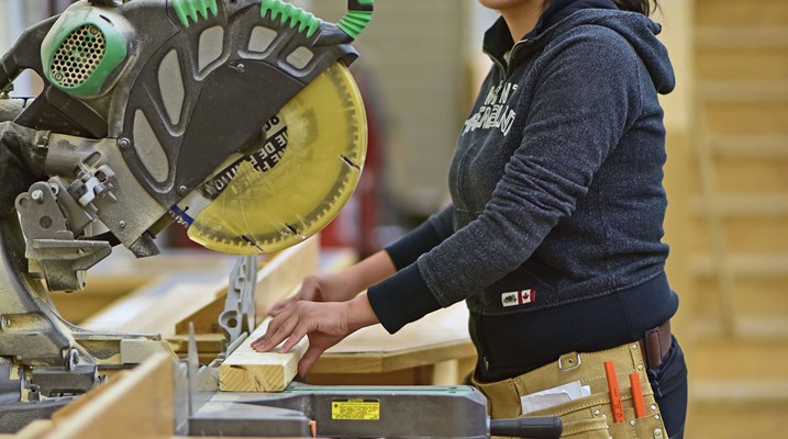 Aboriginal woman using saw in construction lab