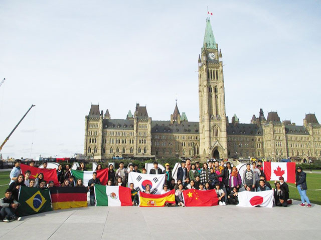 students with flags in front of the parliament building in ottawa