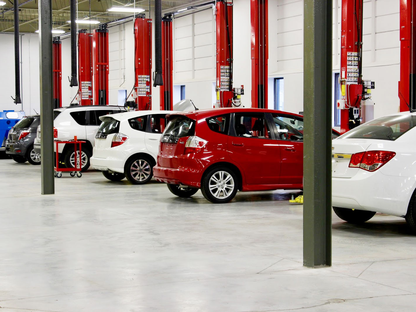 a garage with white and red cars in the parking