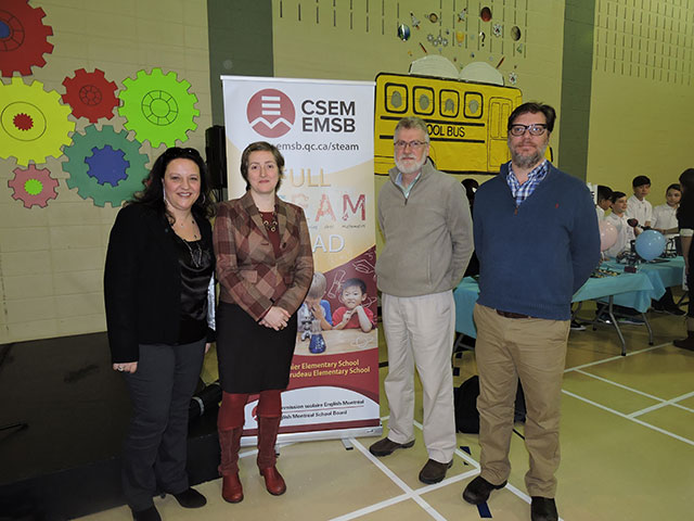 four people standing in front of a EMSB banner