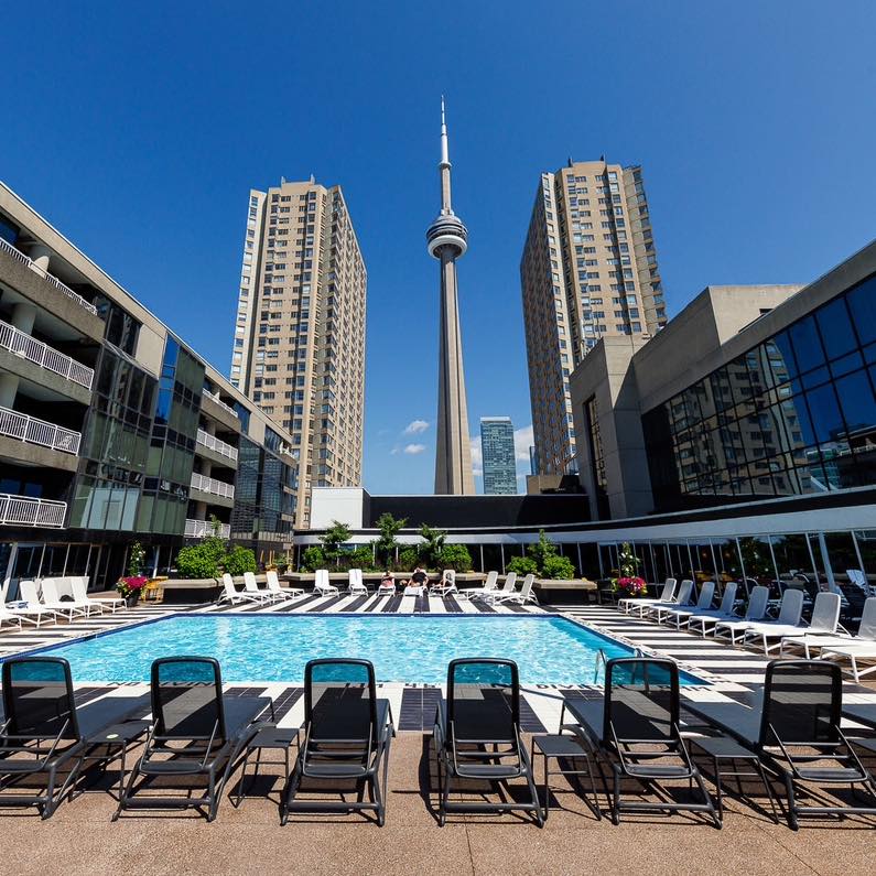 View of a poolside at the Radisson Blu. A number of deck chairs are arrayed around the water.