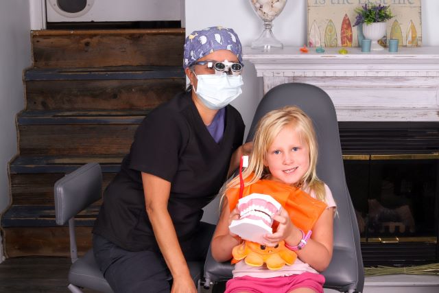 Using a plastic model, mobile dental hygienist Joy Maderazo teaches Emma St-Laurent the ideal way to brush her teeth, while comfortable at home.  Photo courtesy of Joy Maderaz