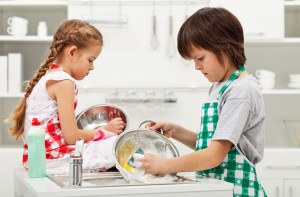 Grumpy kids doing home chores on parents order - washing dishes