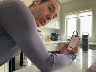 Joel caught mid-scroll on his phone in the kitchen, running a Claude Code remote control session