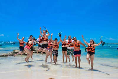 The Agility CMS team jumping on the beach in life vests, ready to snorkel