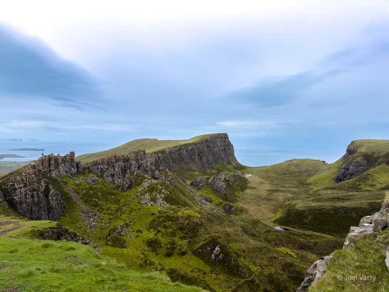 The flat top of the Quiraing escarpment running off into the distance, a little lochan tucked into the valley below