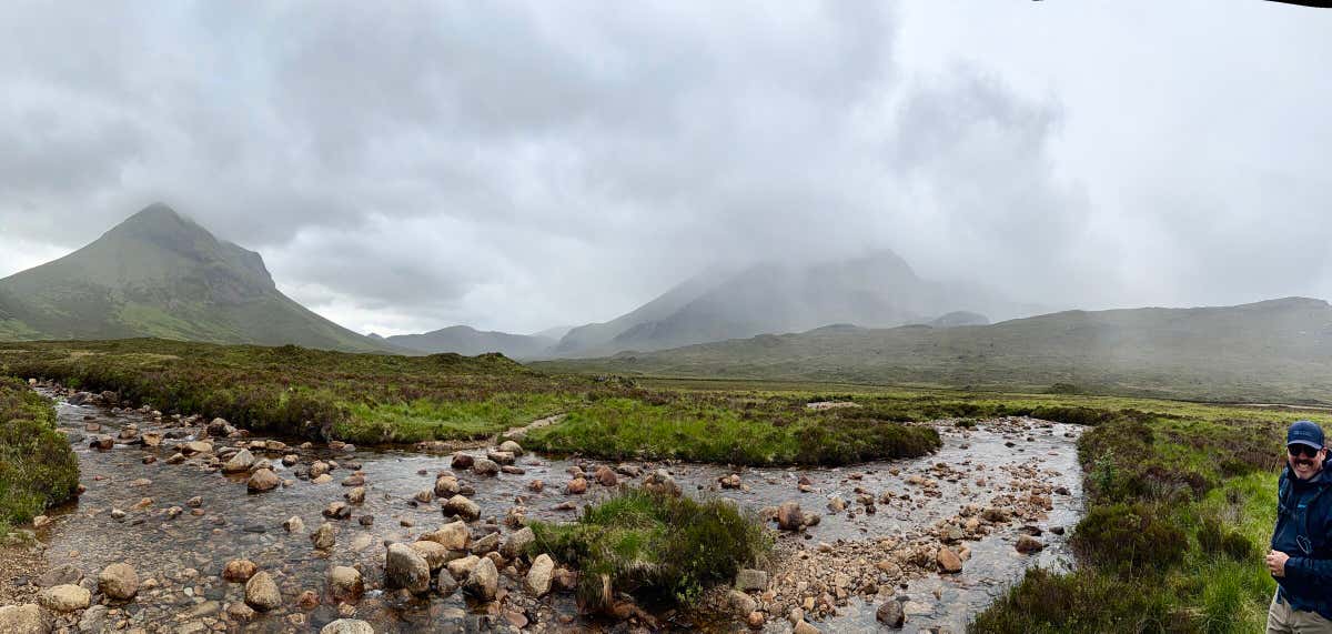 A panorama looking up the glen, the Allt Dearg Mor running through the stones, rain rolling in over the peaks