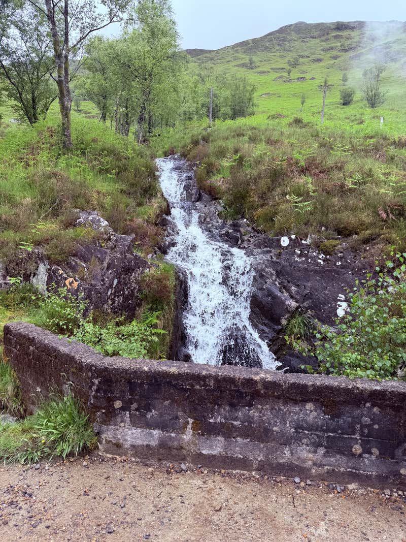 A small waterfall running past an old stone wall
