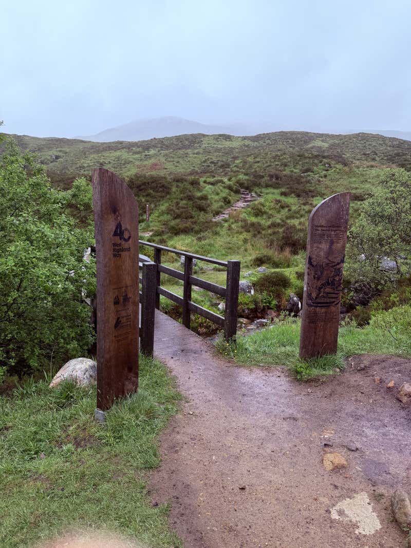 A stile over a fence and another marker pointing the way
