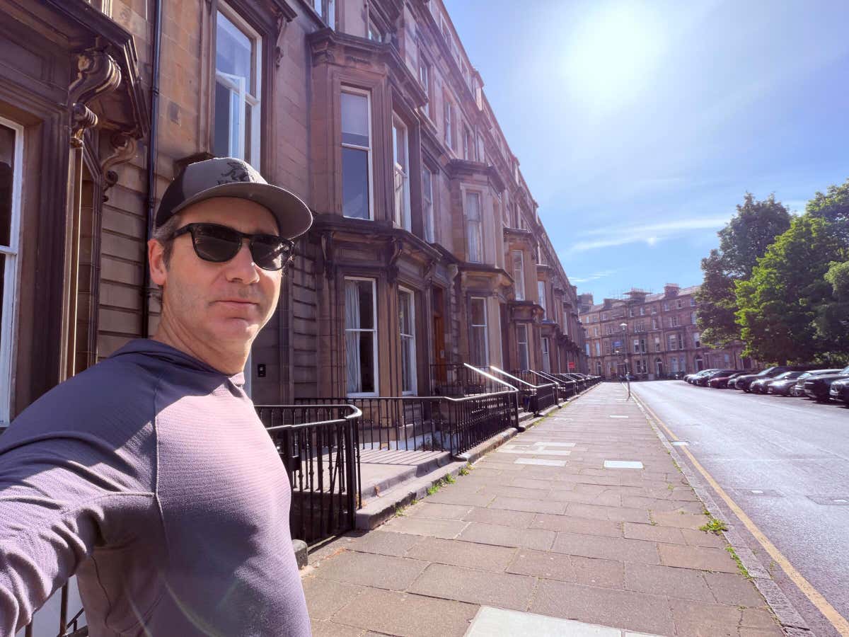 Standing on a quiet Edinburgh street lined with sandstone townhouses, morning sun overhead